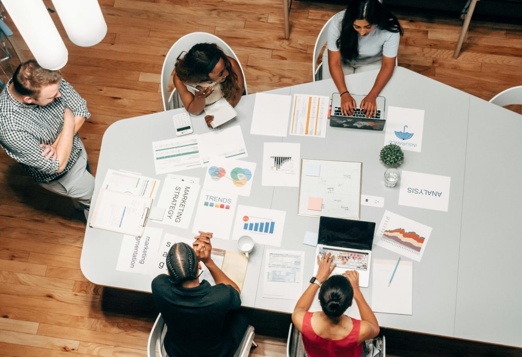 A diverse group working on marketing strategies with charts and laptops in an office setting.